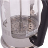 Nærbillede af Bialetti stempelkande med glasbeholder, metalfilter og sort håndtag i minimalistisk produktfoto.