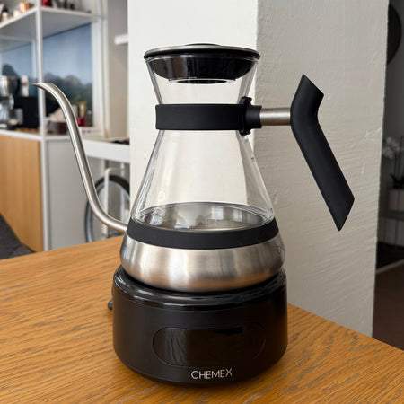 Elkedel fra Chemex i moderne design i glas og sort bund. Udstillet i cafe miljø