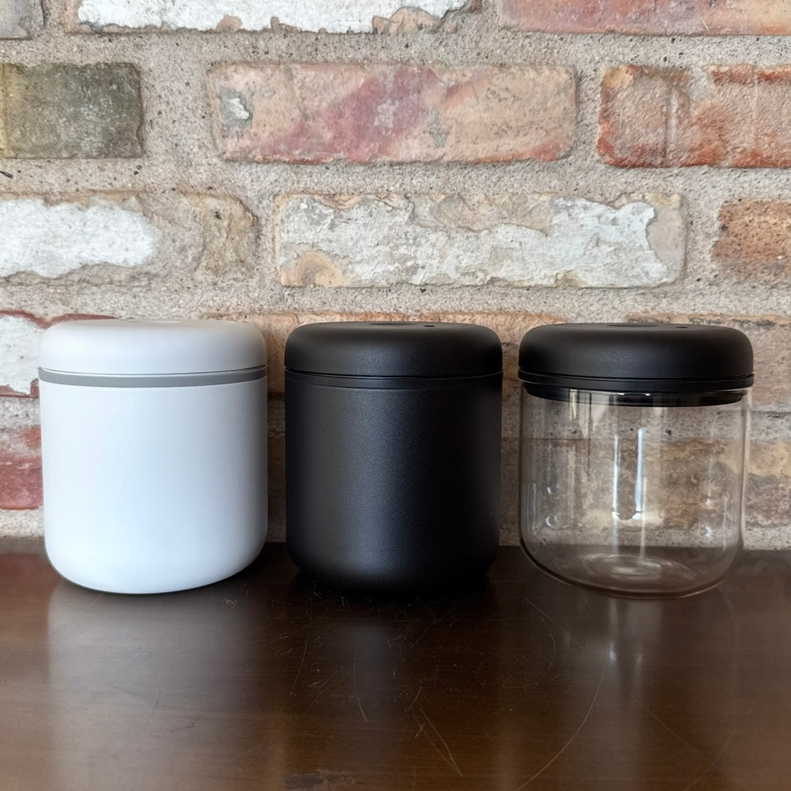 Tre vakuumbeholdere til kaffe i hvid, sort og transparent design for optimal opbevaring.
