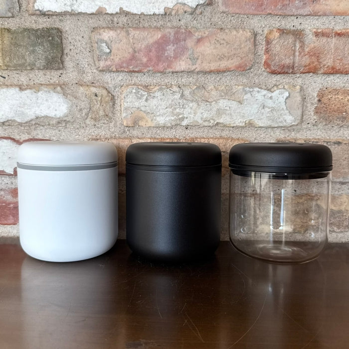 Tre vakuumbeholdere til kaffe i hvid, sort og transparent design for optimal opbevaring.
