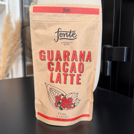 Pose med Fonte Guarana. Cacao Latte pulver i naturlig papirindpakning placeret i moderne café- og butiksmiljø.